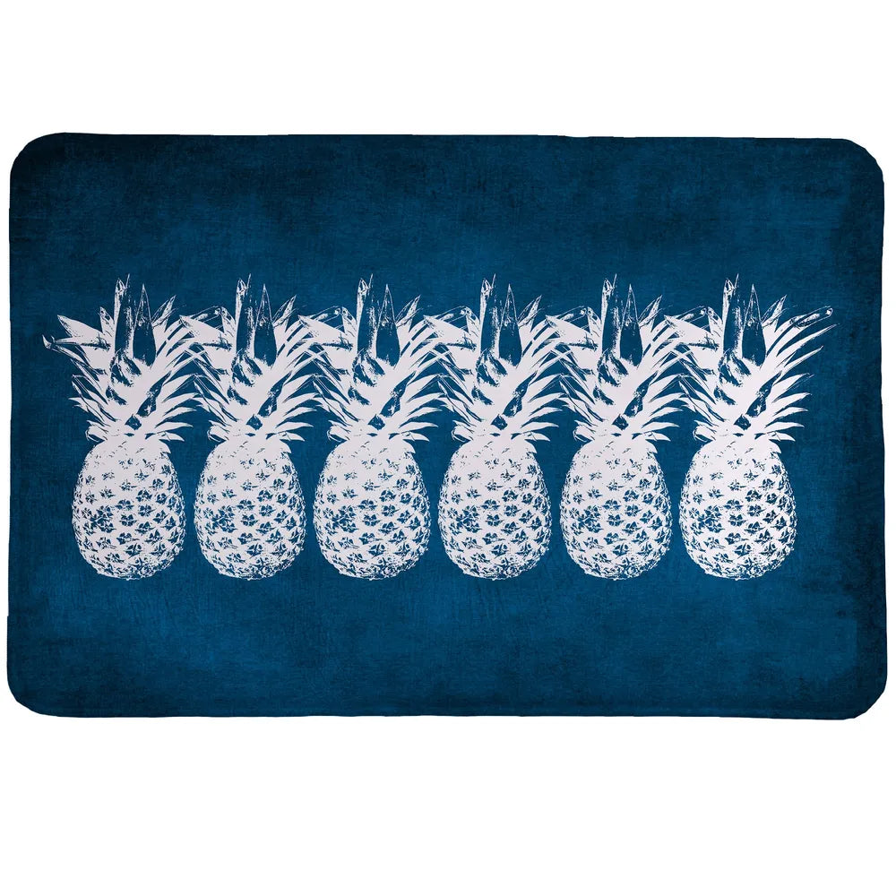Indigo Pineapples Memory Foam Rug features a row of white pineapples standing out against a deep indigo blue background