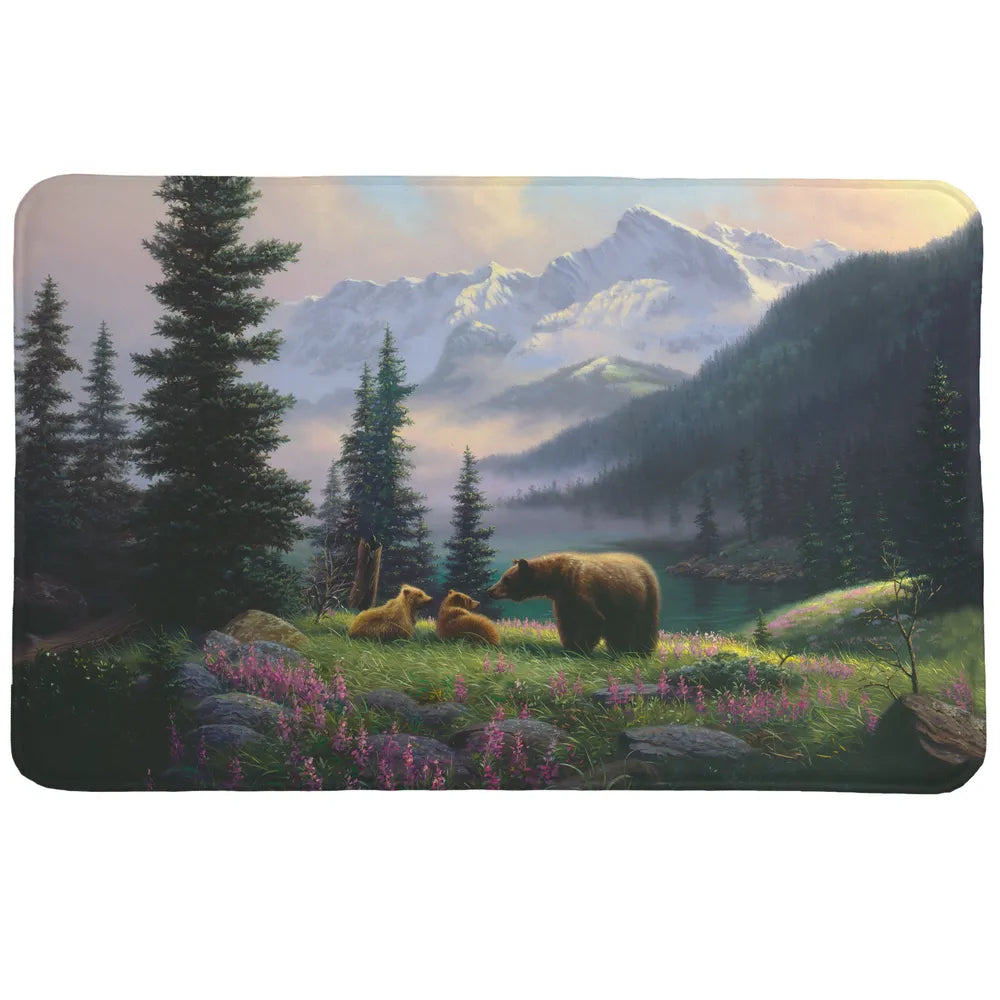 Mountain Bear with Cubs Memory Foam Rug has a majestic and serene mountain landscape that features a brown bear and her two cubs in a field of purple wildflowers.