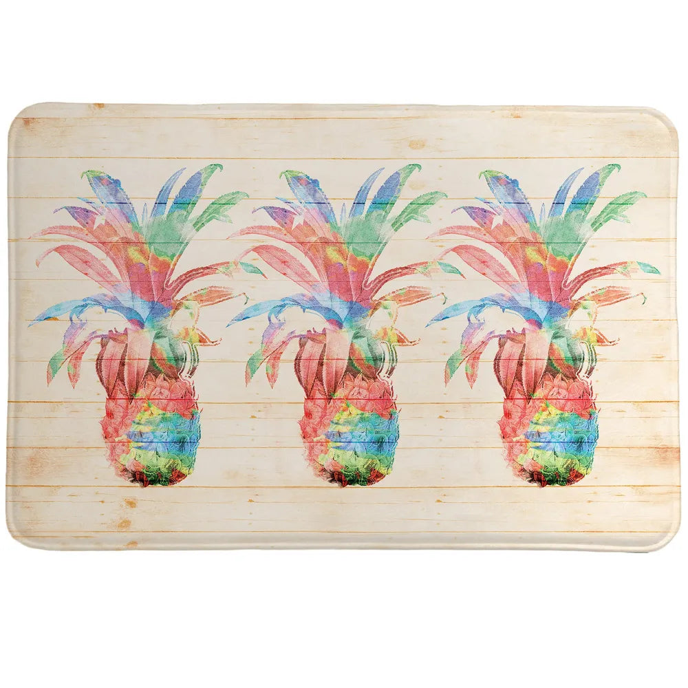 Colorful Pineapples Memory Foam Rug features pineapples set on a textured background designed to look like a wooden board and features splashes of paint.